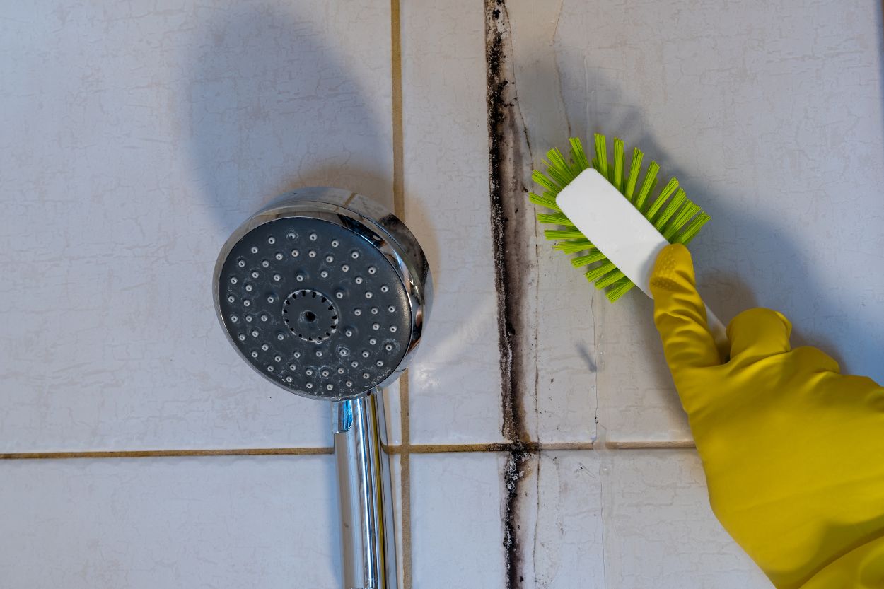 A person diligently cleaning tiles with a brush, part of a water damage restoration effort in Austin, TX.